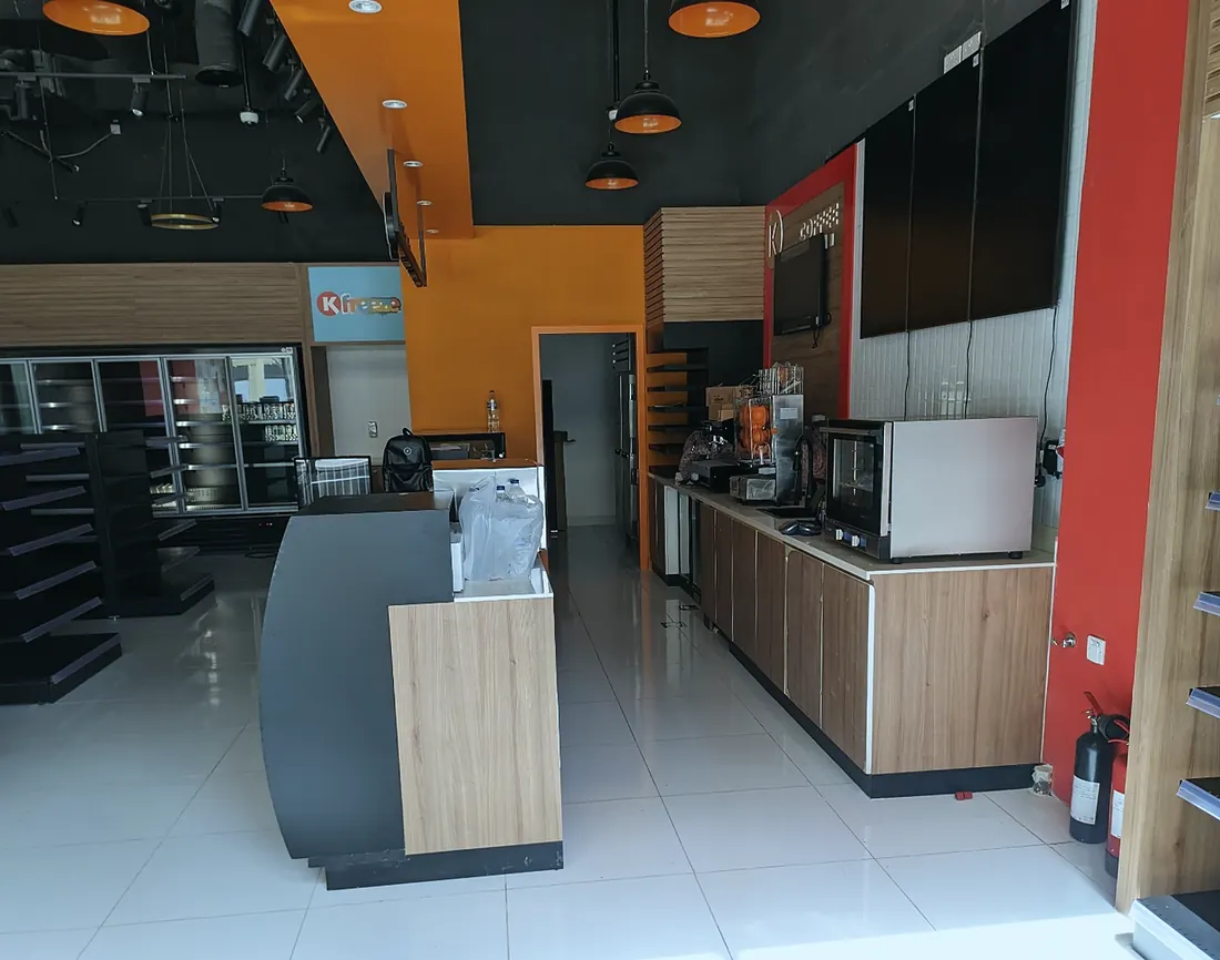 Circle K minimart, Jebel Ali: coffee counter and timber-faced till under pendant lights (frame 1 of 3)