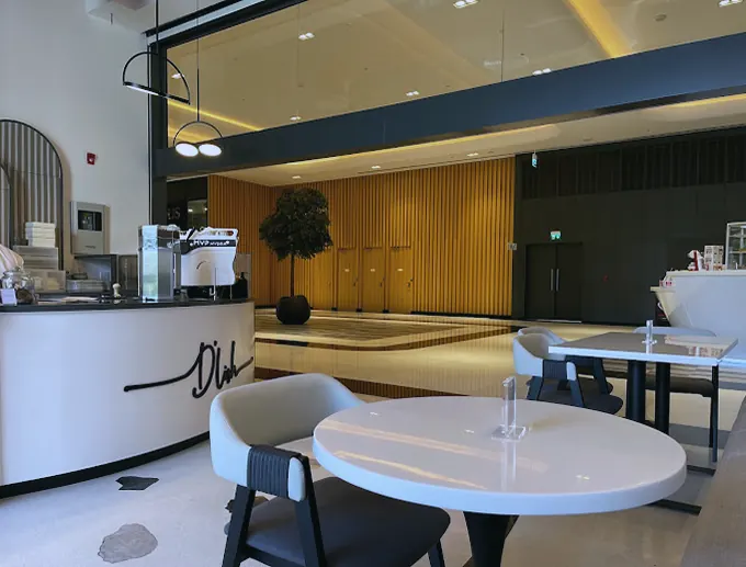 D'Lish cafe, DIFC: white counter with the cafe's script sign, cafe tables and fluted timber (frame 1 of 1)