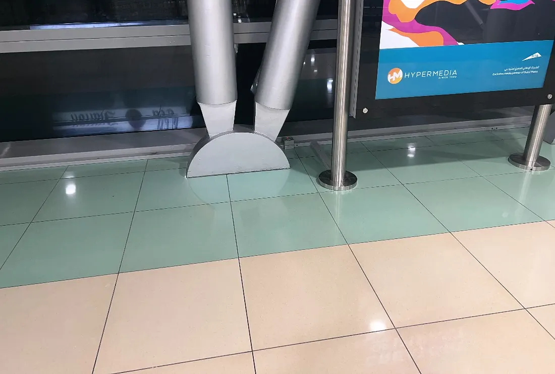 Dubai Metro, Dubai Mall Station: the kiosk screen installed against a station column (top cropped: a name on the on-screen ad) (frame 1 of 2)