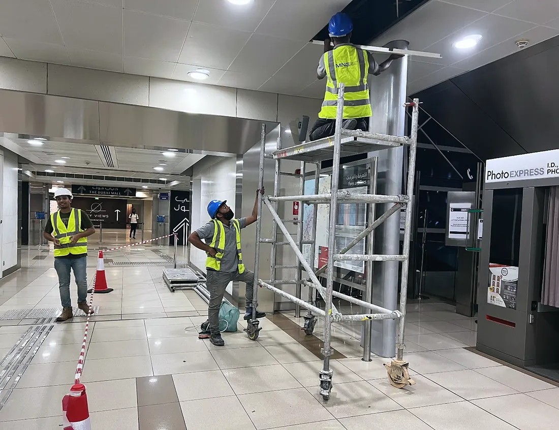Site: the crew on a tower scaffold at the station kiosk (frame 2 of 2)