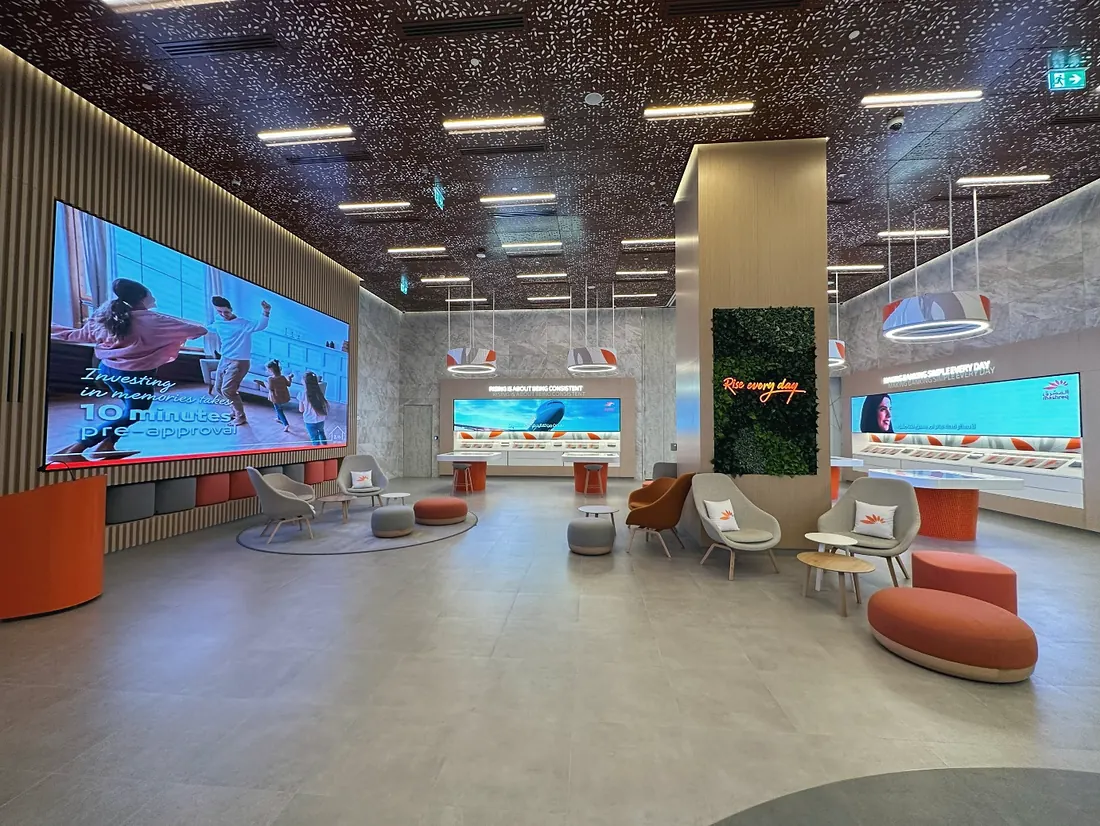 Mashreq Bank branch, Downtown Dubai: curved orange seating, timber-slat wall and a perforated ceiling (frame 1 of 3)