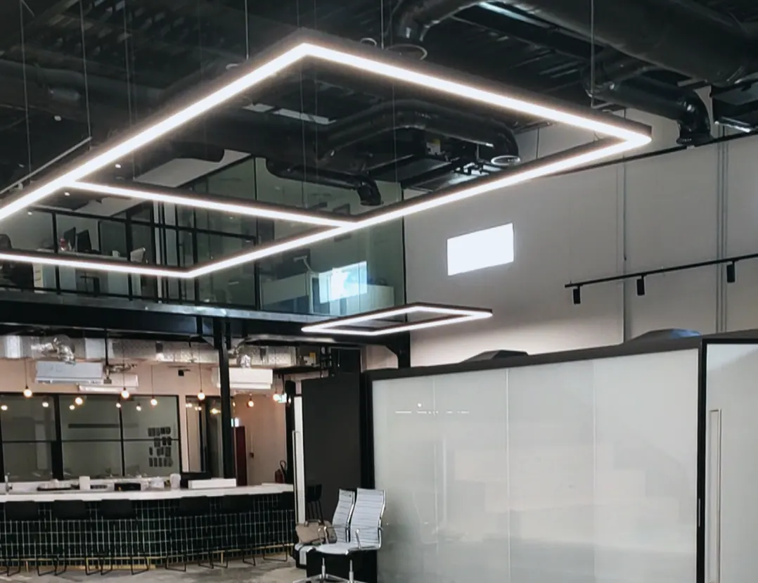 Optima office, Al Quoz: linear light frames over glazed meeting rooms and a green-tiled counter (frame 1 of 2)